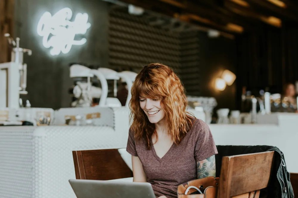 A woman working on a laptop in a café.